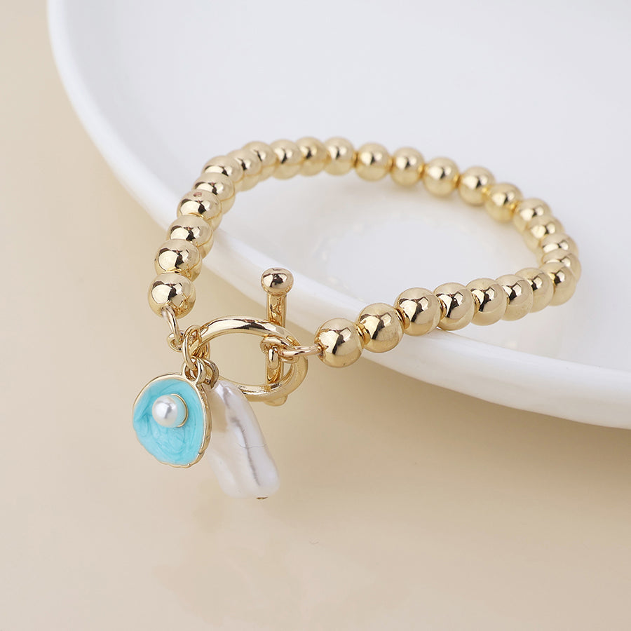 Golden t-bar bracelet with shell and pearl charms